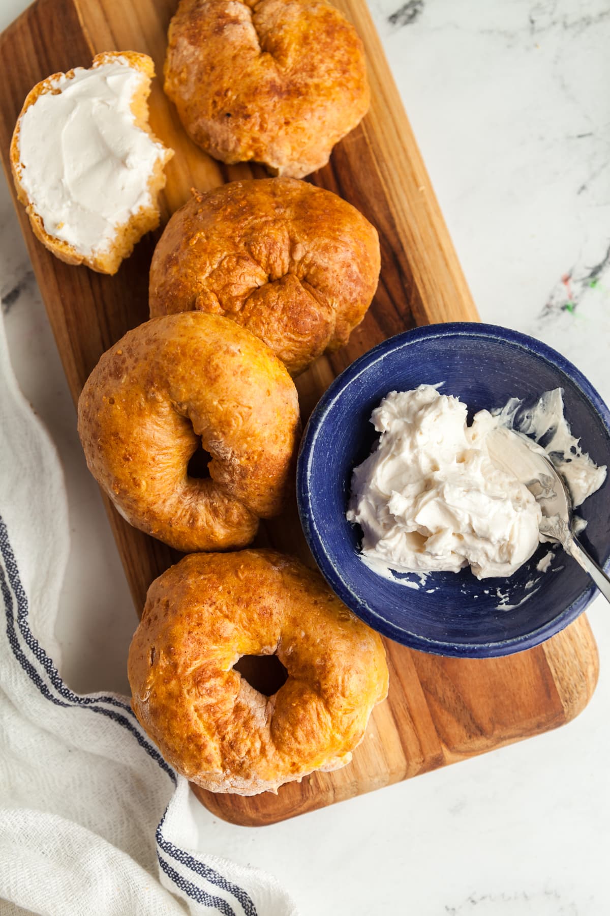 Overhead view of pumpkin bagels on a wooden board.