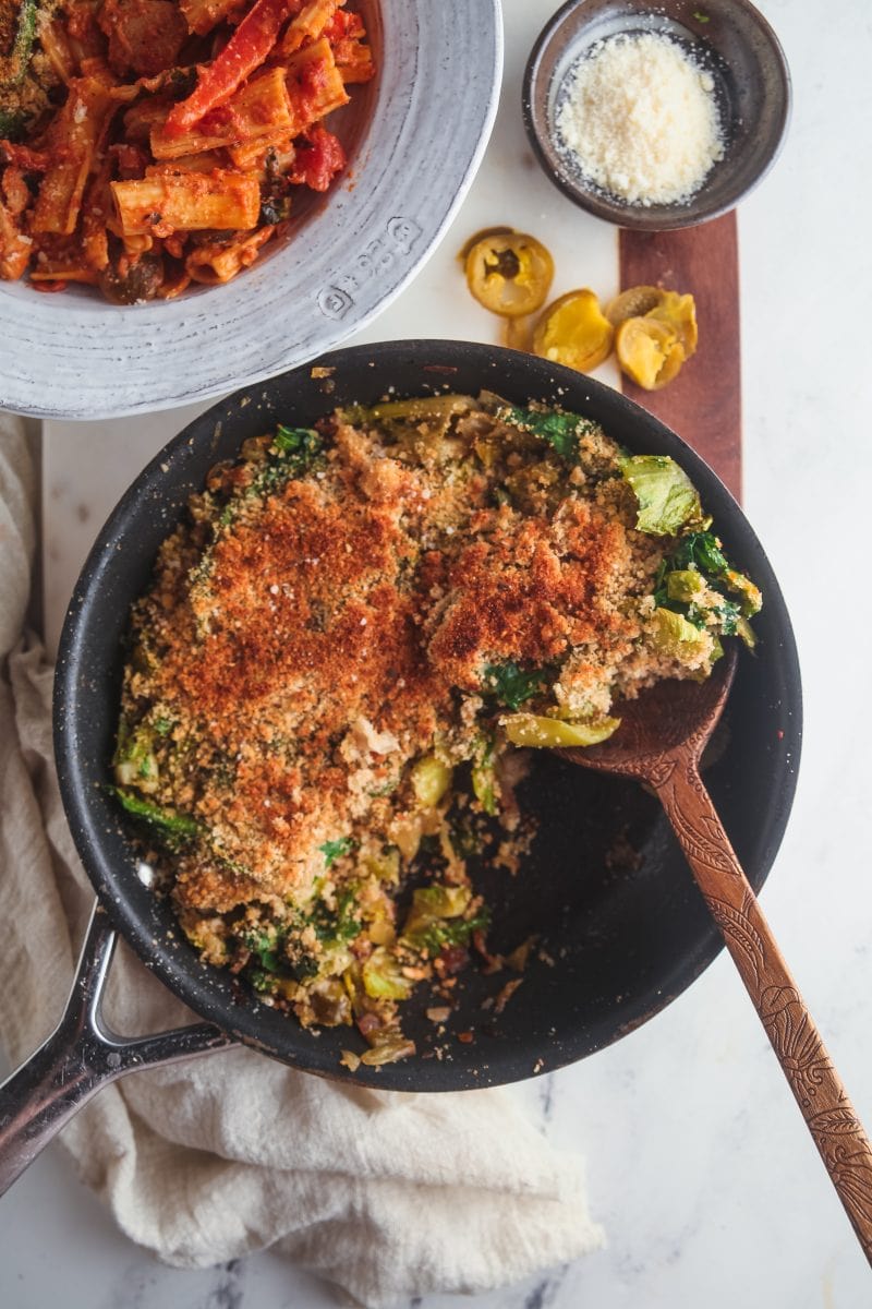 Overhead view of a skillet filled with Utica greens with a scoop being taken out.