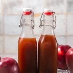 Two glass bottles of apple cider syrup, side by side on a kitchen counter.