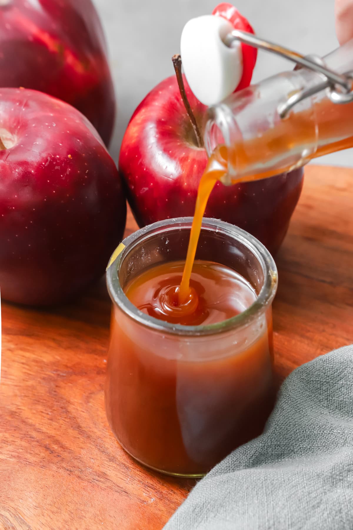 Pouring boiled apple cider into a small glass jar. 