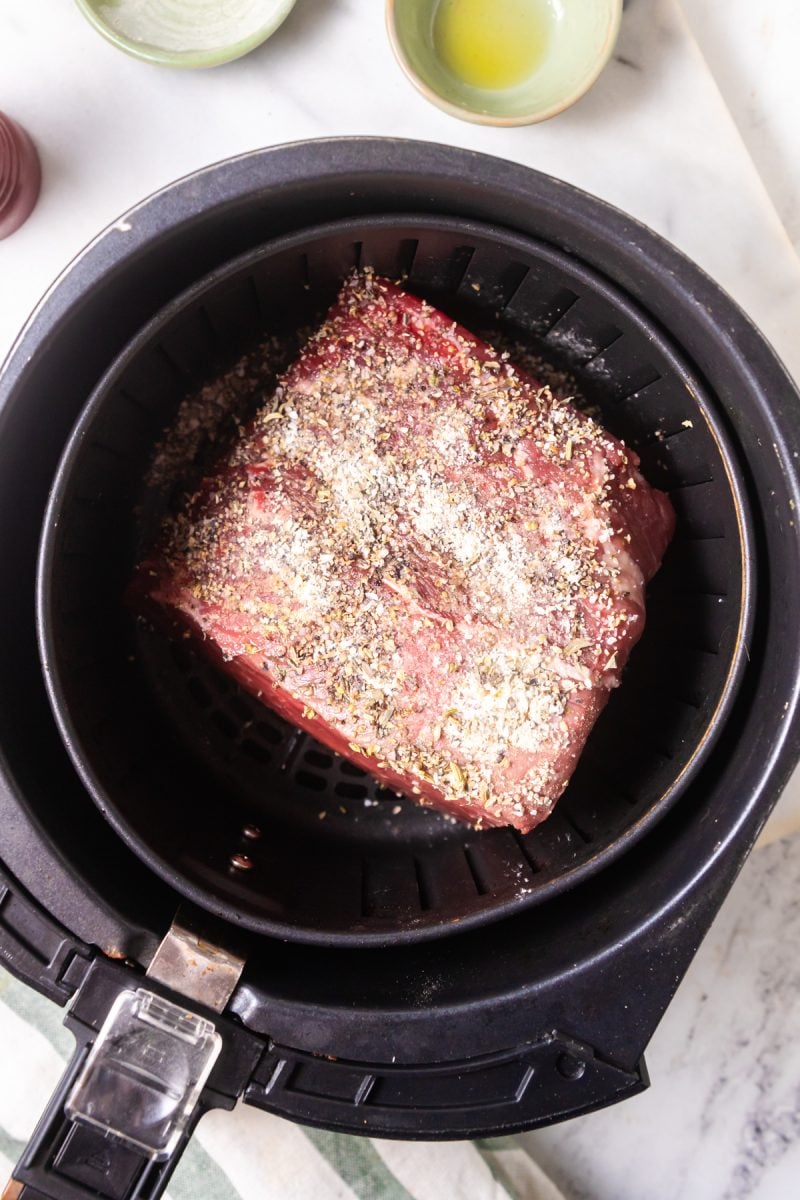 Raw roast beef in an air fryer basket. 